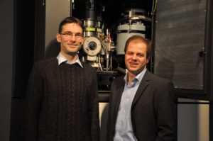 Dr. Benjamin Butz und Prof. Erdmann Spiecker vor dem aberrationskorrigierten Titan³ 80-300, das sie für die mikroskopische Untersuchung der Versetzungen in Bilagen-Graphen einsetzten. (Bild: FAU)