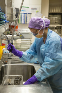 A member of staff pre-cleans the instruments in the decontamination zone before they are washed. (Image: FAU/Georg Pöhlein)