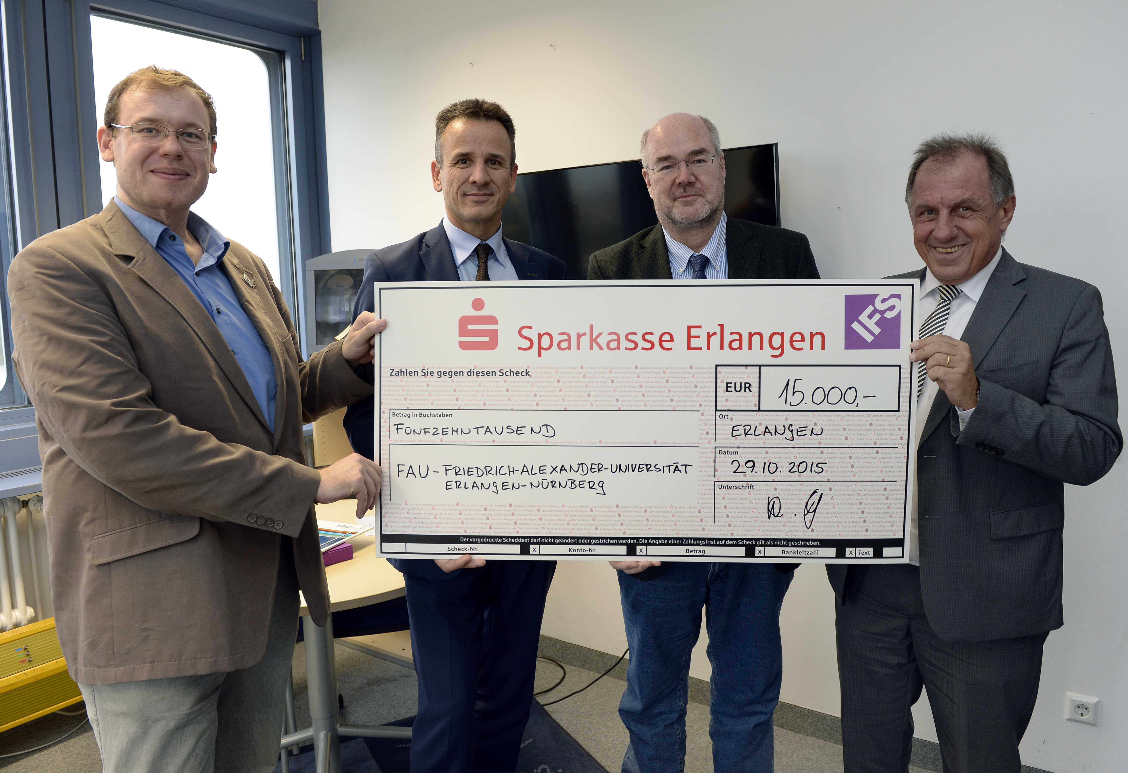 Einen Scheck in Höhe von 15.000 Euro übergibt Herbert Feuchtinger (2.v.r.), Vice President Consulting & Support von IFS Europe Central, an PD Dr. Peter Wilke (2.v.r.) vom Lehrstuhl für Mustererkennung am Department für Informatik der FAU. Die Universität wird die Spende überwiegend zur Beschaffung von Software nutzen, um die Ausbildungsqualität für ihre Studierenden weiter zu verbessern. Mit im Bild: Prof. Prof. Andreas Maier (li.), Leiter des Lehrstuhl für Mustererkennung der FAU, und IFS Europe Central CEO Wilfried Gschneidinger. (Bild: FAU/Harald Sippel)