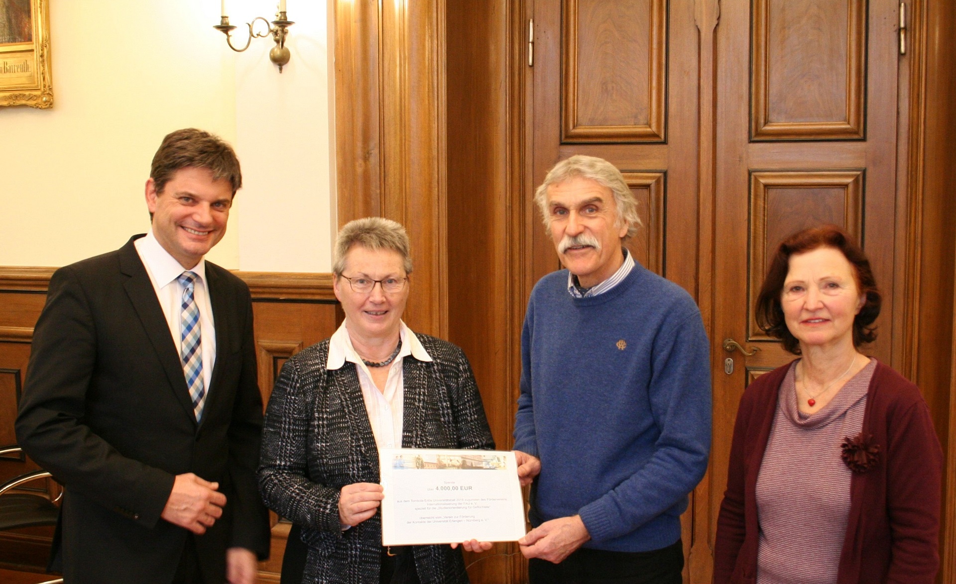 Prof. Dr. Joachim Hornegger, Präsident der FAU, Dr. Brigitte Perlick, Leiterin des Referats für Internationale Angelegenheiten, Dr. Thomas Krusche, Stellvertretender Leiter der Allgemeinen Studienberatung, Ursula Ertl, Organisatorin des Universitätsballs mit dem Check zugunsten der FAU-Flüchtilingsprogramms (Bild: FAU/Boris Mijat)