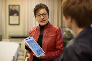 Direktorin Konstanze Söllner spricht mit einem Tablet in der Hand mit einer anderen Person