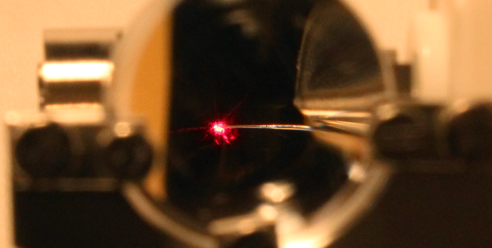Blick durch eine Linse: Eine Nanospitze wird von einem Laserstrahl getroffen. (Bild: Dr. Michael Förster)