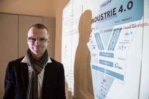 „Für beide Seiten eine runde Sache“ Jörn Fahsel vor einem Plakat zur Industrie 4.0