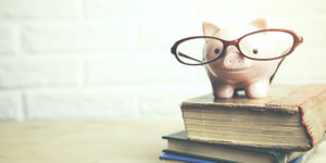 Sparschwein mit Brille auf Büchern