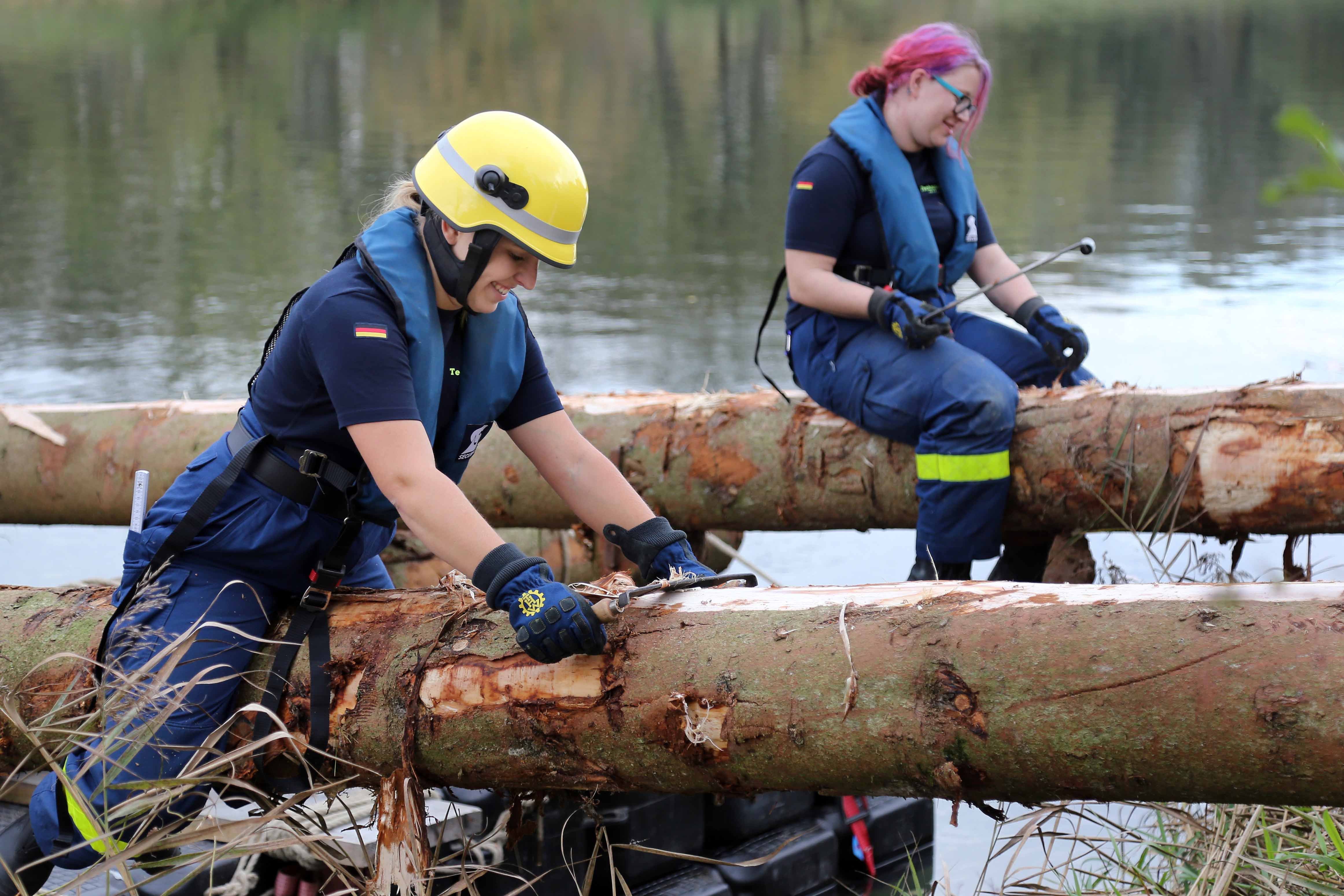 Helferinnen des Technischen Hilfswerks beim Entrinden der Baumstämme. (Bild: FAU/Matthias Orgeldinger)