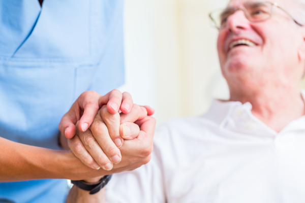 Krankenschwester hält die Hand eines Rentners