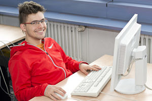 Mathe-, Physik- und Informatik-Student Kevin Höllring sitzt an einem Tisch mit Computerbildschirm und Tastatur