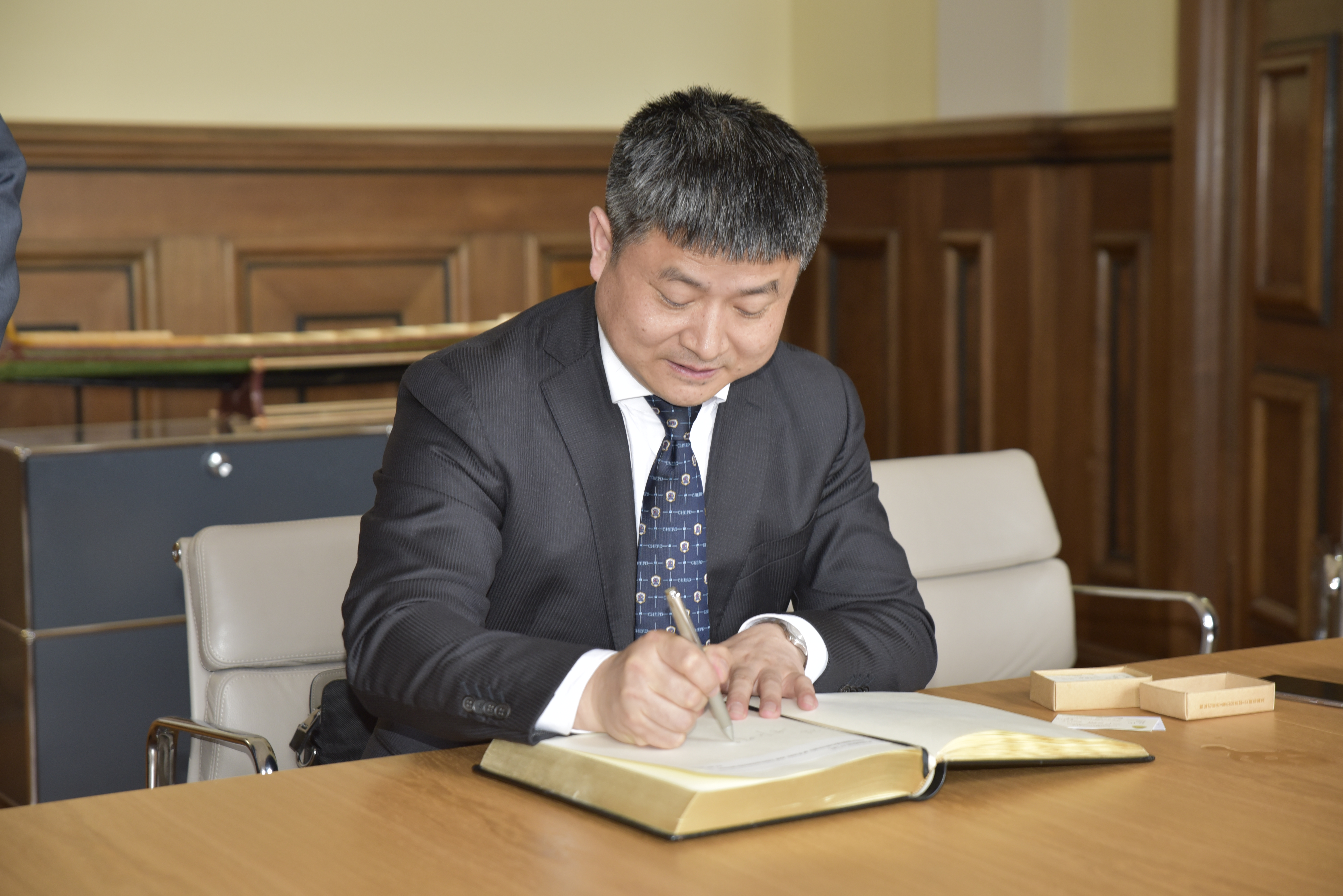 Der Präsident der Chinqing University of Posts and Telecommunications (CQUPT) trägt sich in das Gästebuch der FAU ein. (Bild: FAU/Rebecca Kleine Möllhoff)