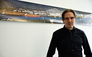 Künstler in seinem Büro; an der Wand hängt eine Collage aus Panoramafotos