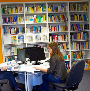 Student studying at a table with the library in the background