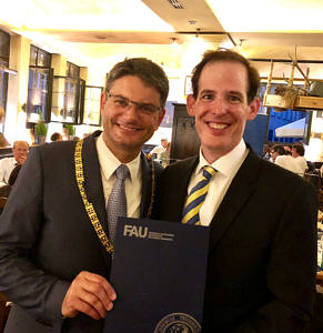 Gemeinsames Bild mit Prof. Dr. Joachim Hornegger (links) und Dr. Paul Gumminger (rechts): Prof. Dr. Joachim Hornegger zeigt eine blaue Umschlagsmappe mit FAU-Logo.