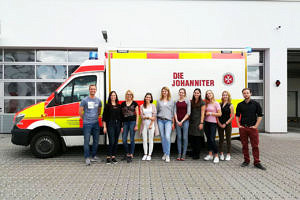 Eine Gruppe von Menschen steht vor einem Rettungswagen.