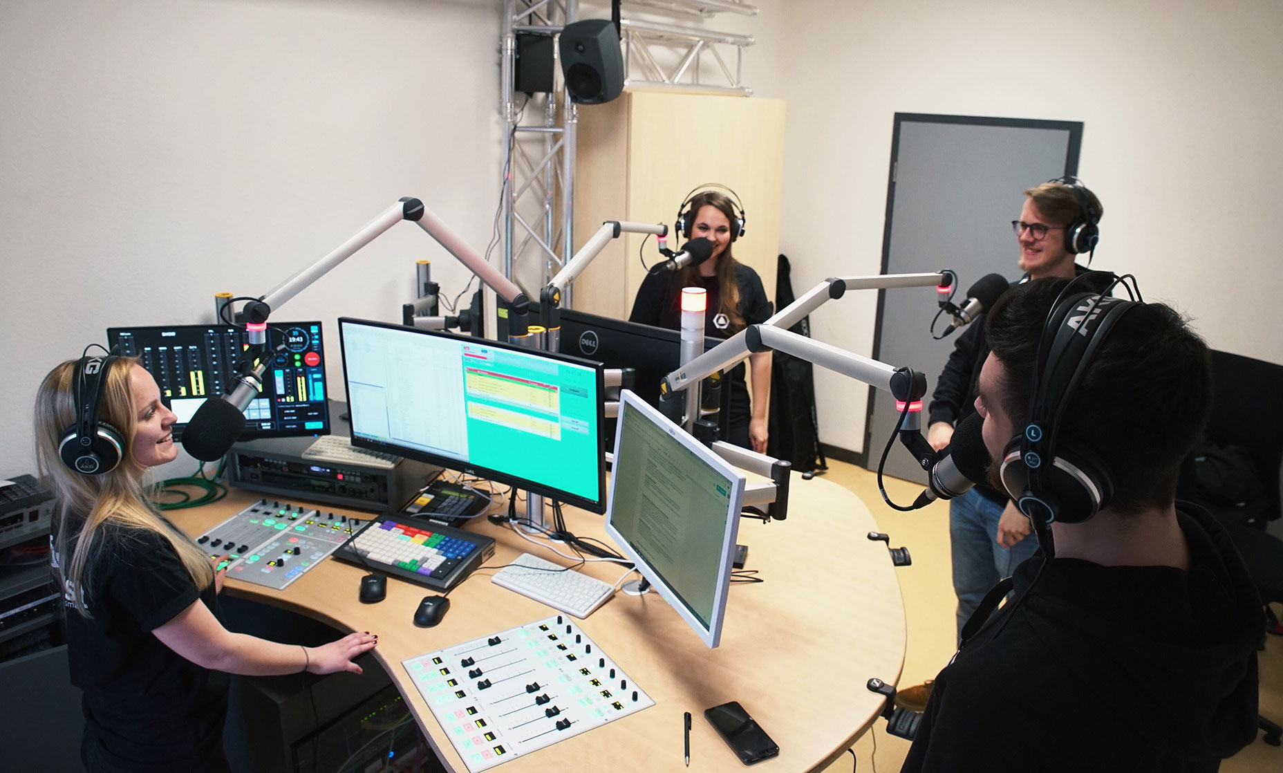 Vier Redakteure im Rundfunkstudio.