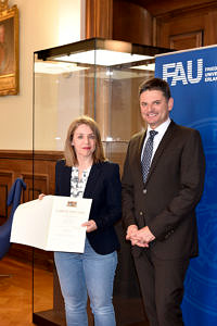 Portraitbild mit Mitarbeiterin (links) und Uni-Präsident: Stolz präsentiert sie ihre Urkunde