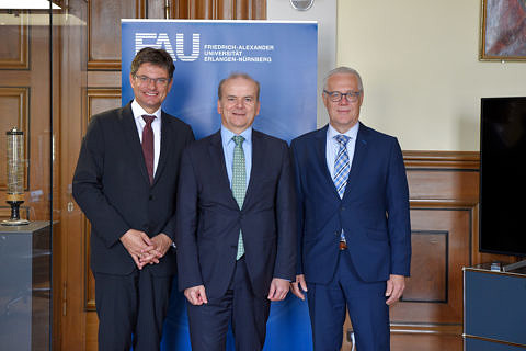 Gruppenbild mit Prof. Dr. Joachim Hornegger (links), Dr. Rolf-Dieter Jungk (mitte) und Christian Zens (rechts) vor einem blauen Rollup.