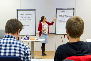 Lecturer standing in front of a flip chart with students