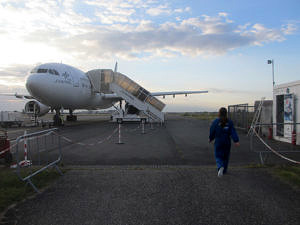 Ina Becker auf dem weg zum Flugzeug: rechts im Bild ist sie von hinten zu sehen, links im Bild ist das Flugzeug abgebildet.