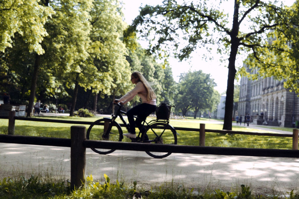 Studentin fährt mit dem Fahrrad durch den Schlossgarten.