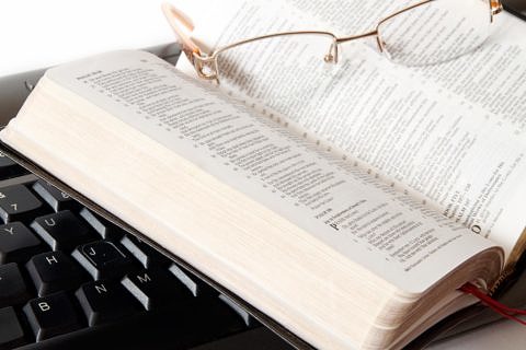 Eine aufgeschlagene Bibel liegt auf einer Tastatur.