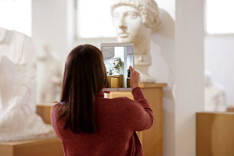 Studentin fotografiert mit einem Tablet eine antike Büste.
