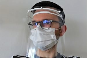 Mann mit Mundschutz und mehreren Visieren