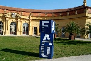 Blaue Würfel mit FAU-Logo vor der Orangerie.