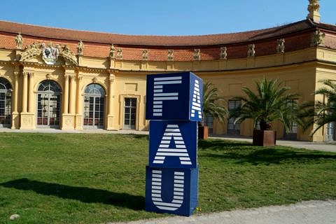 FAU-Logo aus drei übereinanderstehenden Würfeln vor der Orangerie