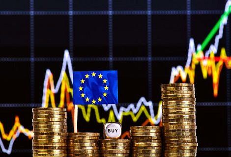 Stacks of gold coins, the EU flag, dice cube with the word "buy"