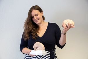 Prof. Dr. Louisa Kulke hält zwei Modelle des menschlichen Gehirns in der Hand