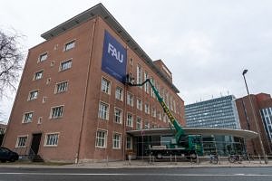 Am Himbeerpalast wird mit Hilfe eines Krans eine FAU-Fahne angebracht.