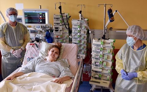 Patientin im Bett, zwei Ärzte daneben