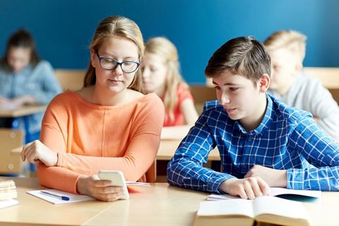 Eine Shcülerin zeigt einem Mitschüler etwas auf dem Handy.