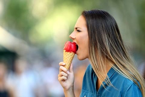 Frau verzieht schmerzvoll das Gesicht während sie ein Eis isst