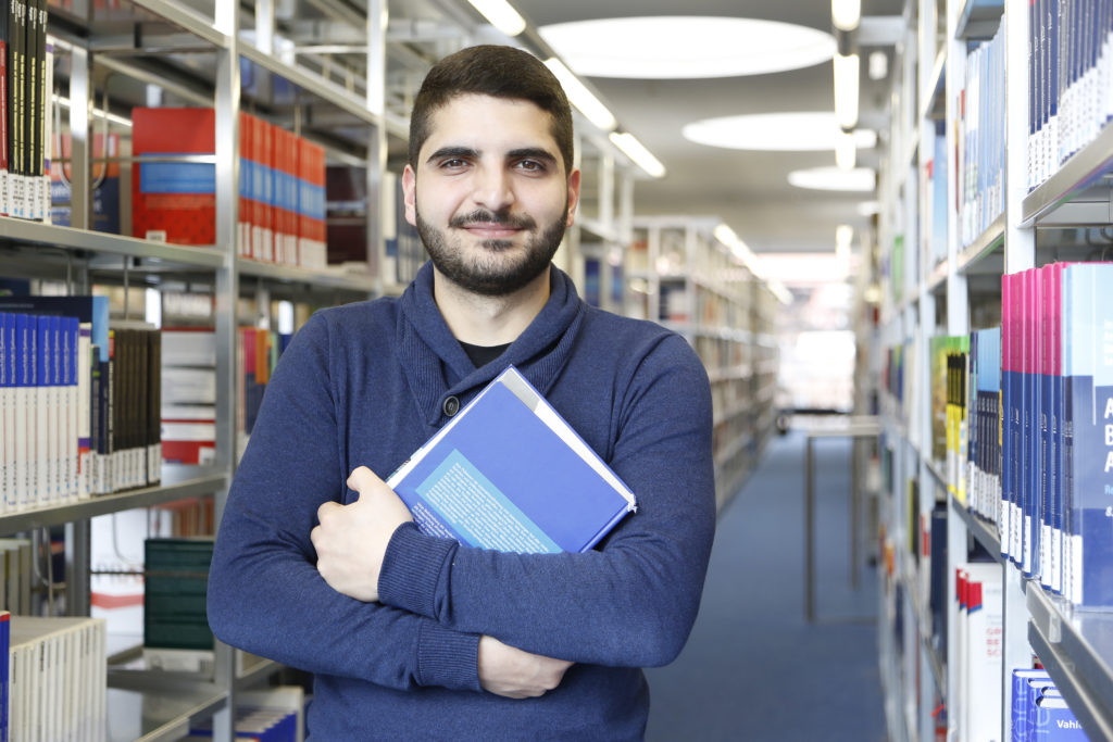 Ein Mann steht in einer Bibliothek.
