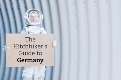 Astronaut mit Schild in den Händen, auf dem "The Hitchhiker's Guide to Germany" steht