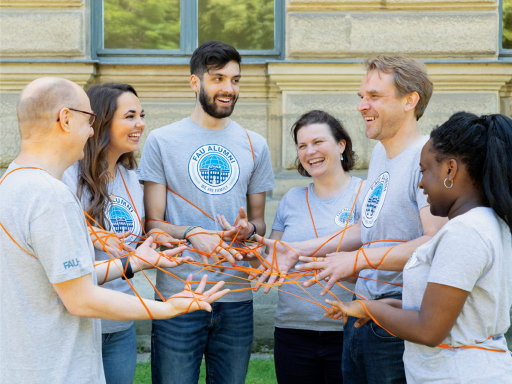 Eine Gruppe von Menschen, die durch ein orangenes Netz miteinander verbunden sind