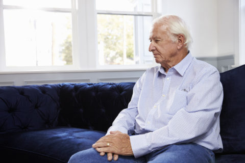 Ein alter Mann sitzt auf einer Couch.