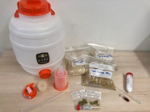 Plastikbottich und verschiedene Tütchen mit Hopfen und anderen Zutaten fürs Bierbrauen