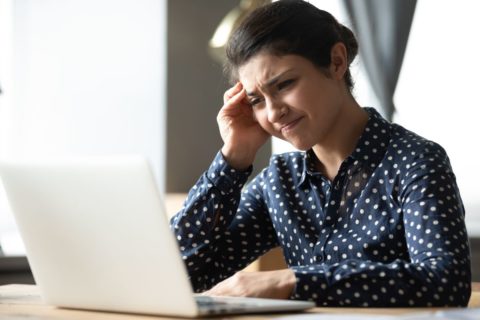 Studentin vor Laptop hält sich den Kopf