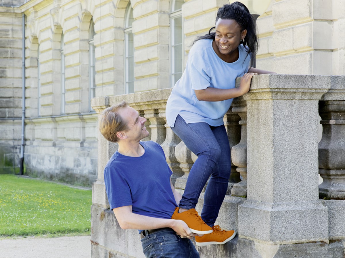 Ein Mann hilft einer Frau über eine Mauer