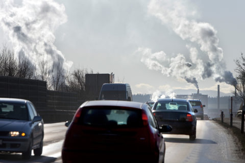 Verkehr auf Straße, im Hintergrund Fabriken und Kraftwerke