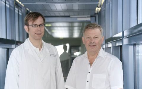 PD Dr. Cord Huchzermeyer (links) und Prof. Dr. Jan Kremer stehen nebeneinander in einem Gang mit Fenstern