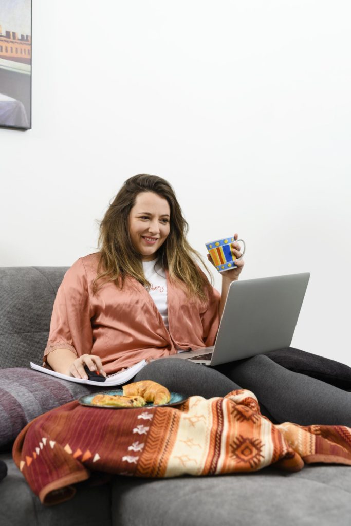 Frau, die im Joginganzug auf dem Sofa sitzt mit ihrem Laptop