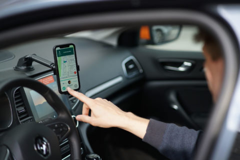 Ein Mann tippt im Auto auf sein Smartphone.