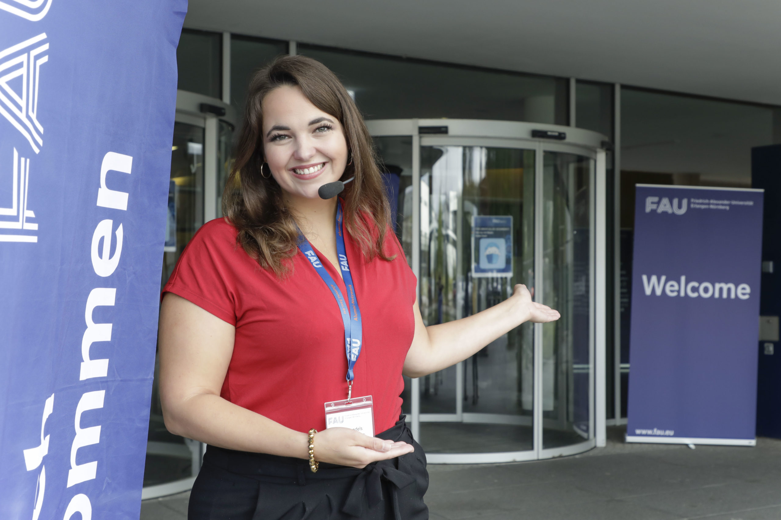 A woman with a headset on is standing in front of a glass door.