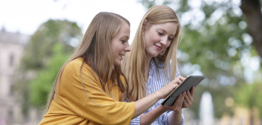 Zwei Studentinnen schauen auf Tablet