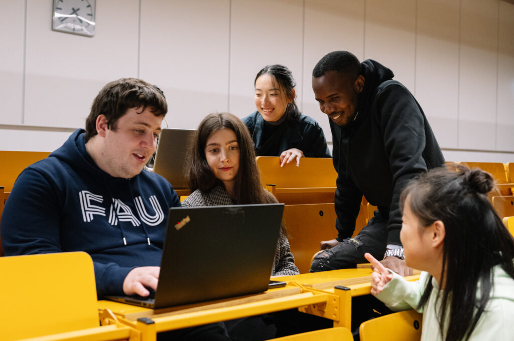 Fünf Studierende der FAU arbeiten gemeinsam in einem Vorlesungssaal.