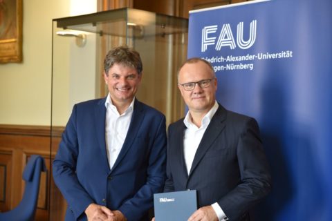 Hornegger und Mayr vor FAU-Rollup im Amtszimmer des Präsidenten der FAU