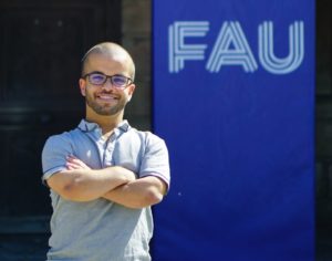 Junger Mann vor FAU-Logo