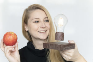 Eine Frau hält einen Apfel und eine Glühbirne in der Hand.